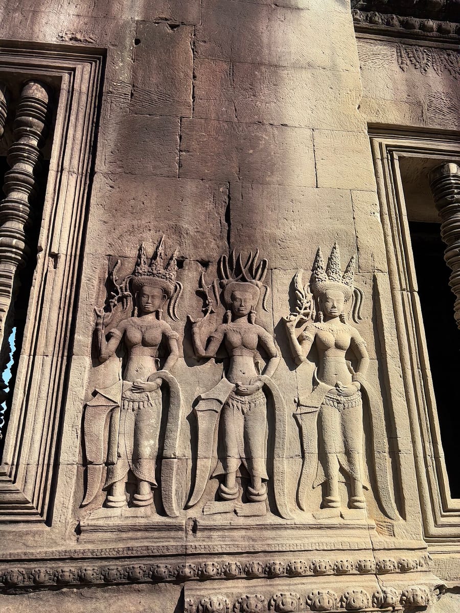Devata figures carved in high relief on a sandstone pillar — among the nearly 1,800 such carvings decorating the temple.