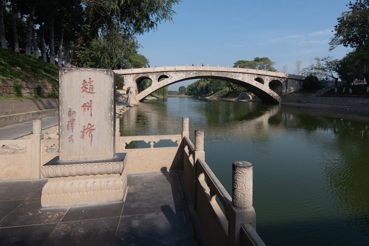 The bridge behind a stone stele bearing its name, Zhaozhou Qiao, at the river's edge.