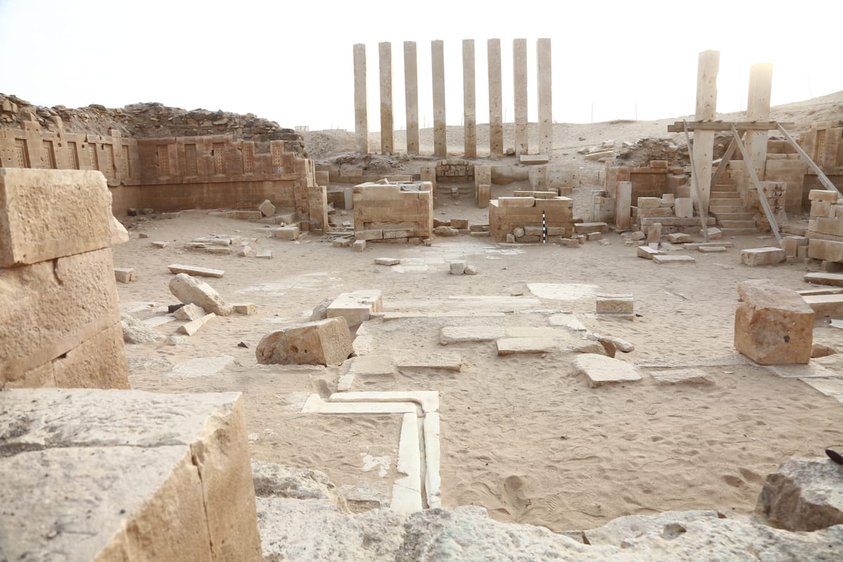 The propylon pillars and the peristyle hall's frieze wall, carved with rows of recessed false windows, in the excavated entrance court.