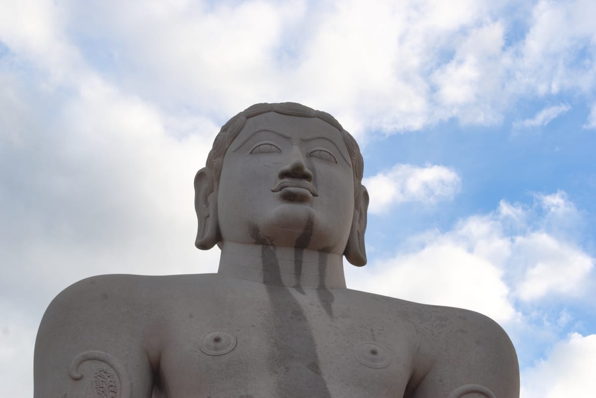 A close-up view of the statue's lower body, showing the madhavi creeper vines carved winding around the legs and arms.