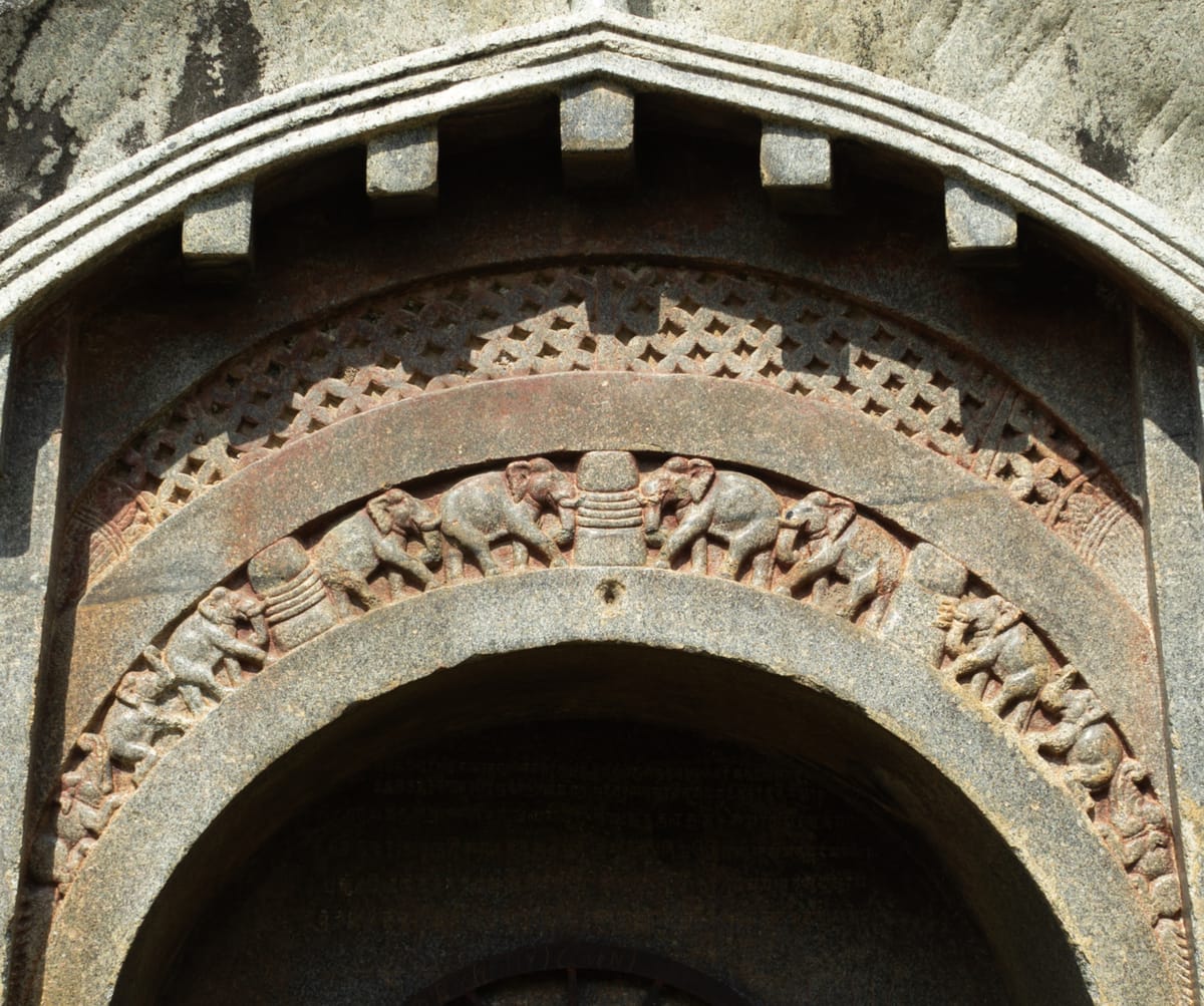 Close-up of the Lomas Rishi entrance, showing the ogee-shaped chaitya arch and elephant frieze carved to imitate wooden architecture.
