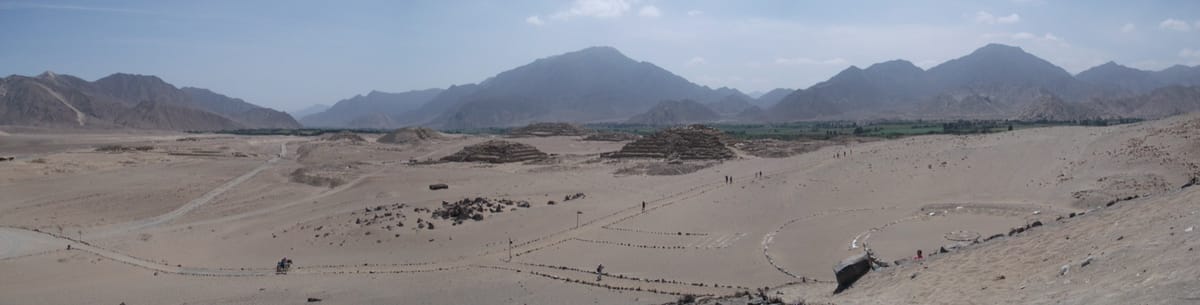 Panorama of the Sacred City of Caral-Supe, showing the spread of monumental mounds and plazas across the 626-hectare terrace above the green Supe River floodplain.