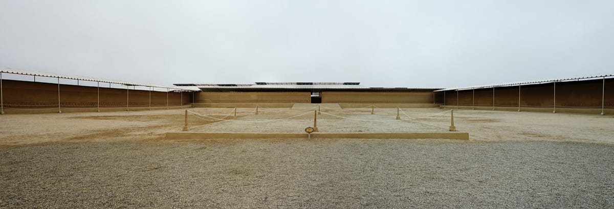 A restored ceremonial plaza in the Nik An (Tschudi) palace compound, showing the high adobe walls of a Chimú ciudadela and their carved friezes.