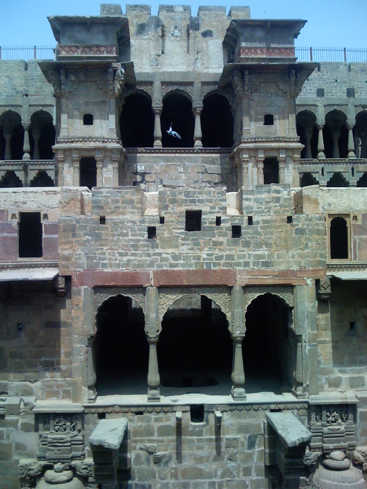 An angled view of Chand Baori's carved sandstone walls and descending staircases.