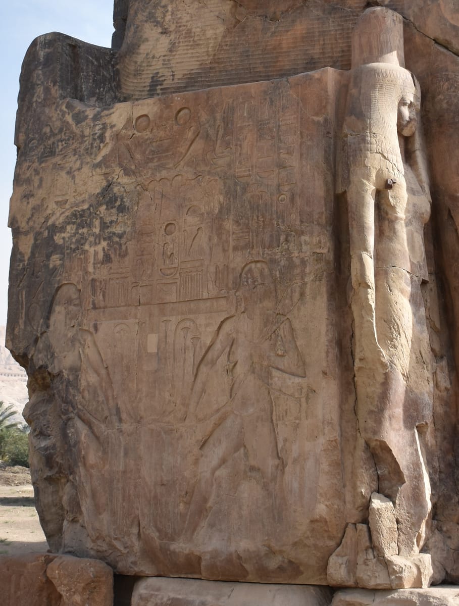 A side panel of one throne. At the sides, two figures of the Nile god Hapi knot together the heraldic plants of Upper and Lower Egypt (the 'sema-tawy' unification motif), beside a smaller standing figure of the royal wife Tiye — one of the family members carved at the pharaoh's legs.