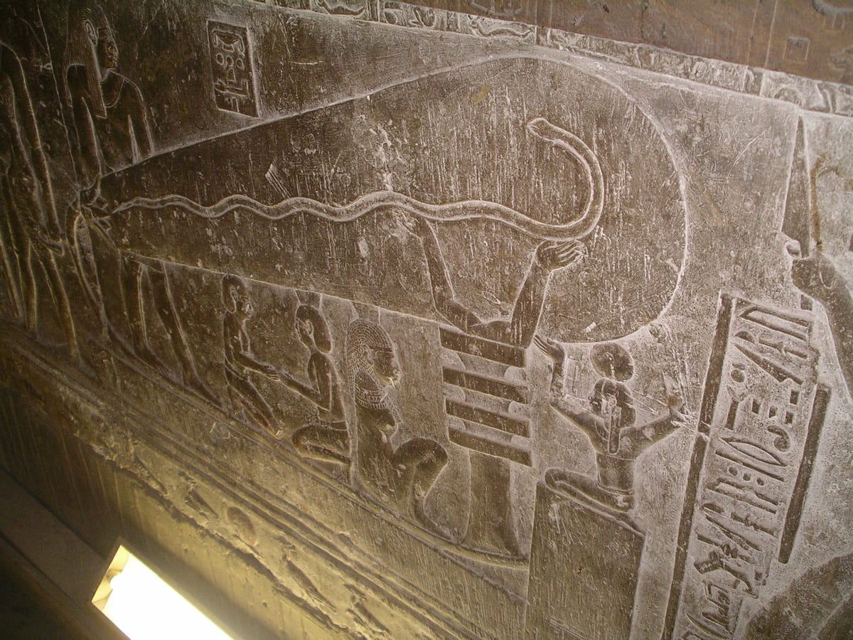 The 'Dendera light' relief in a temple crypt. Fringe writers read the large teardrop shape as an electric bulb and the wavy line inside it as a filament. The hieroglyphs beside it identify the scene as the god Harsomtus, a snake, being born from a lotus flower.