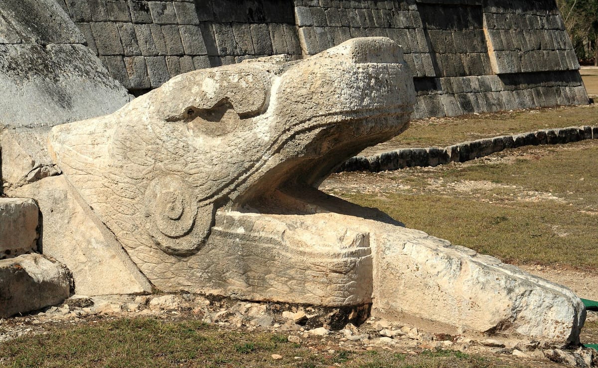 One of the carved serpent heads flanking the base of the northern stairway, where the equinox shadow-serpent comes to rest.