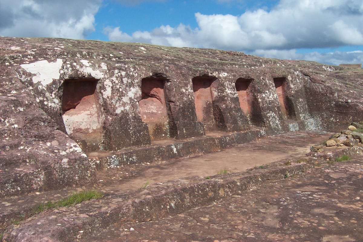 A row of niches cut into the side wall of the sandstone monolith — one of the many recesses carved directly into the living rock.