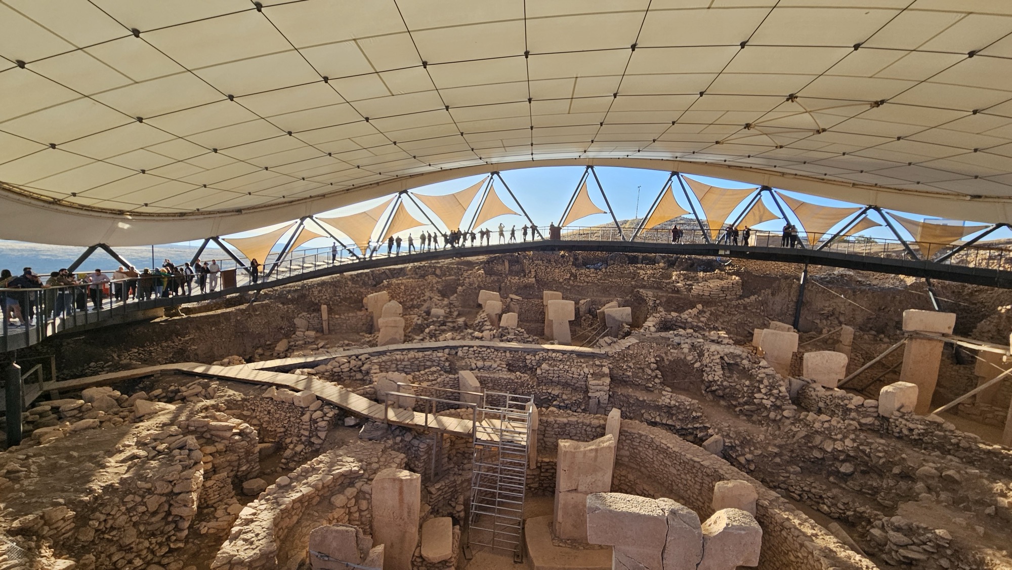 Visitors view the excavated enclosures beneath the protective canopy at the Göbekli Tepe archaeological park.