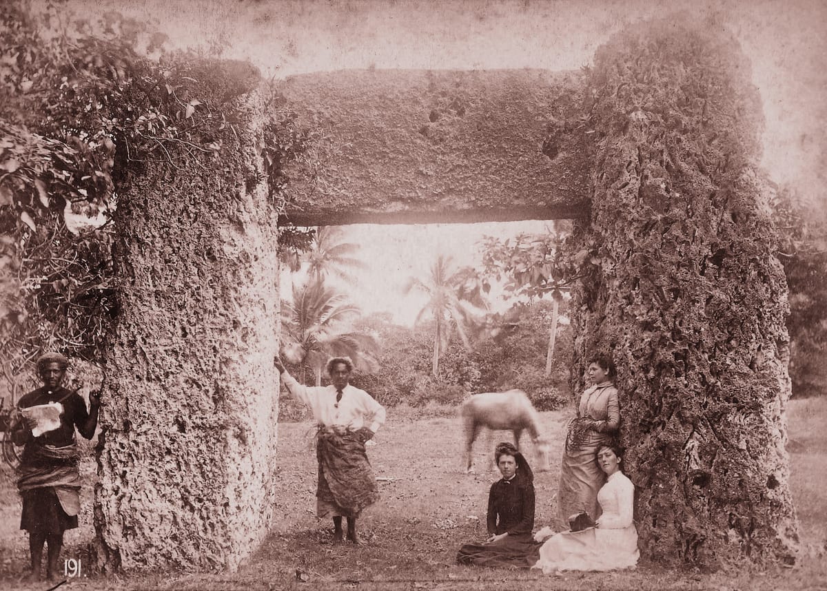 Front view photographed in the 1880s, with a group posed beneath the lintel for scale — the trilithon then still half-swallowed by vegetation.
