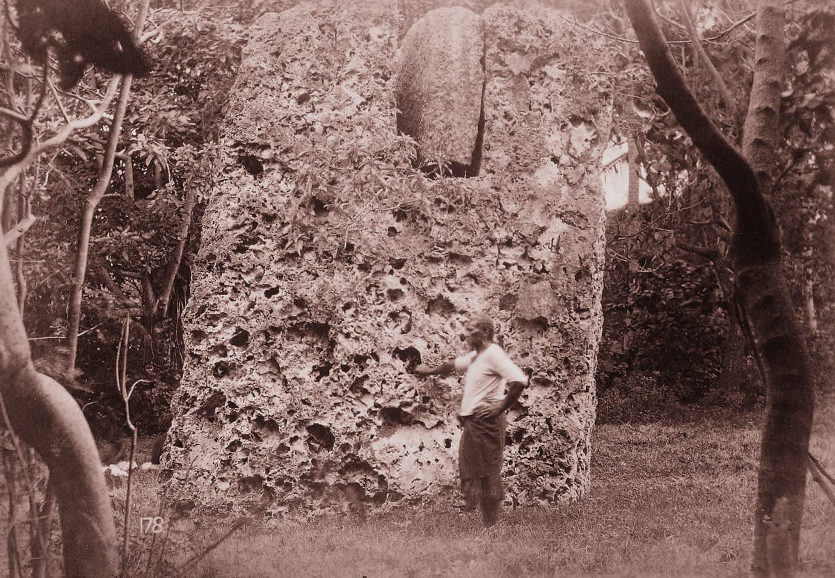 A 19th-century side view of a single upright, with the end of the lintel resting in its mortise slot above and a man standing at the base for scale.