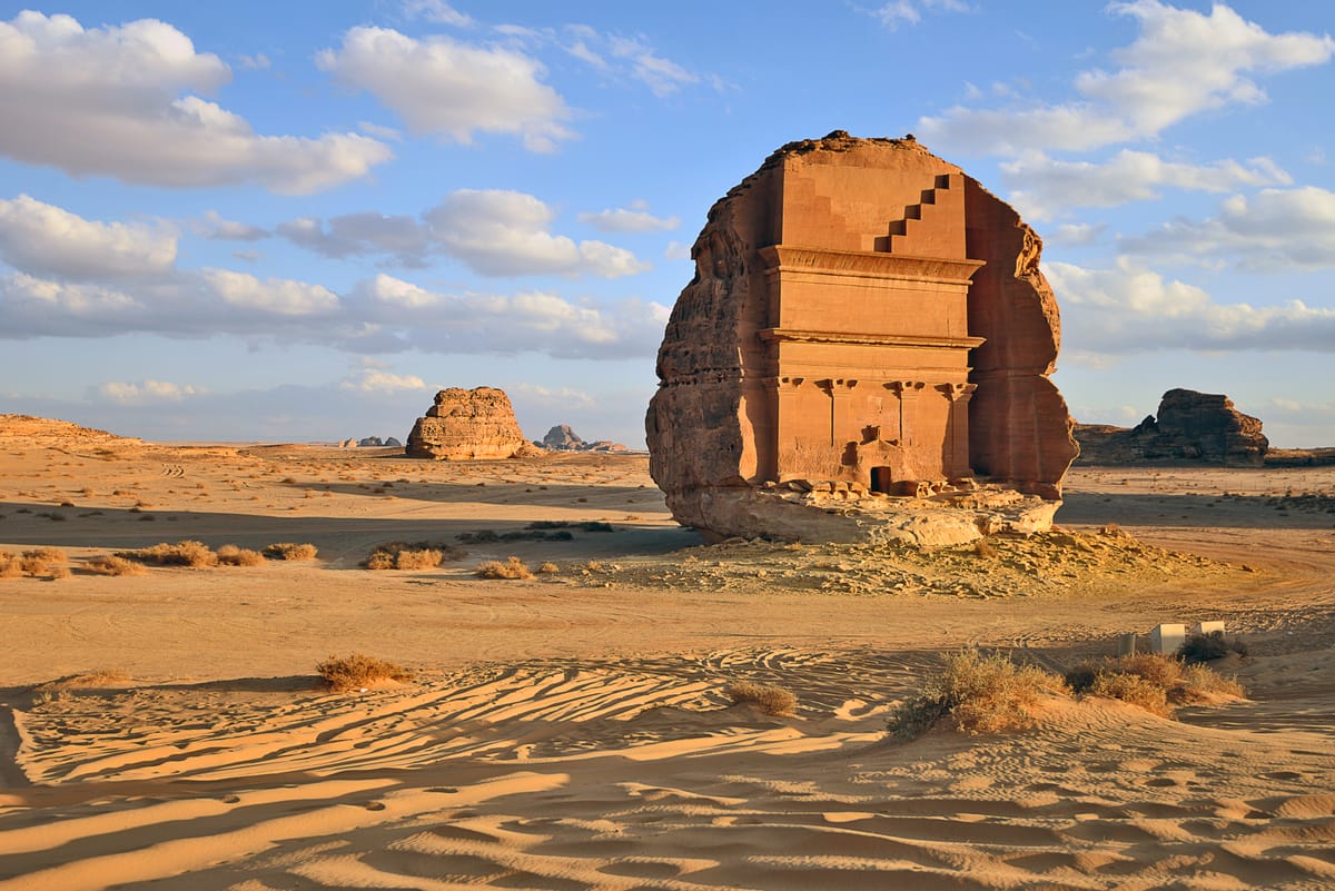 Qasr al-Farid at golden hour, standing alone on the desert floor — the outcrop was carved on all visible sides, a rare freestanding example of the Nabataean rock-cut tomb.