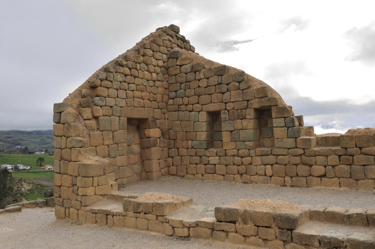 The dressed, mortarless masonry of the Temple of the Sun's upper chamber — fitted stone blocks framing trapezoidal niches and a doorway, the wall curving to follow the elliptical plan.