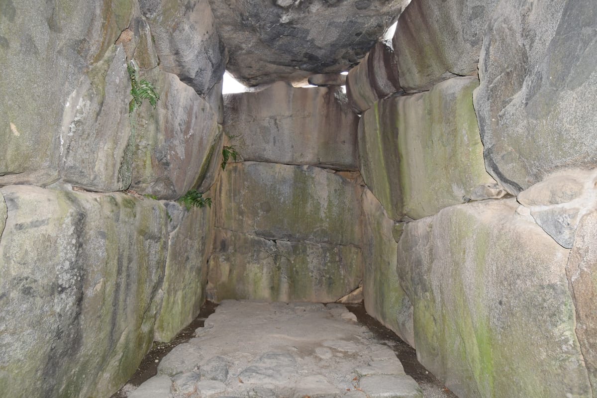 Inside the burial chamber, looking toward the rear wall: granite blocks fitted without mortar, roofed by the ceiling stones.