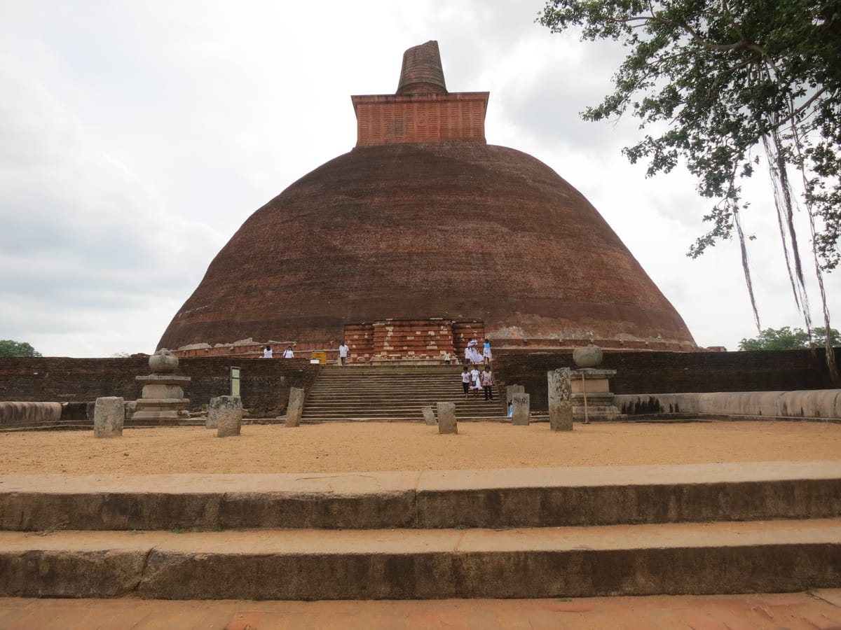 The stupa from its paved terrace, with visitors on the stairs giving a sense of the roughly 100-metre span of the dome at platform level.