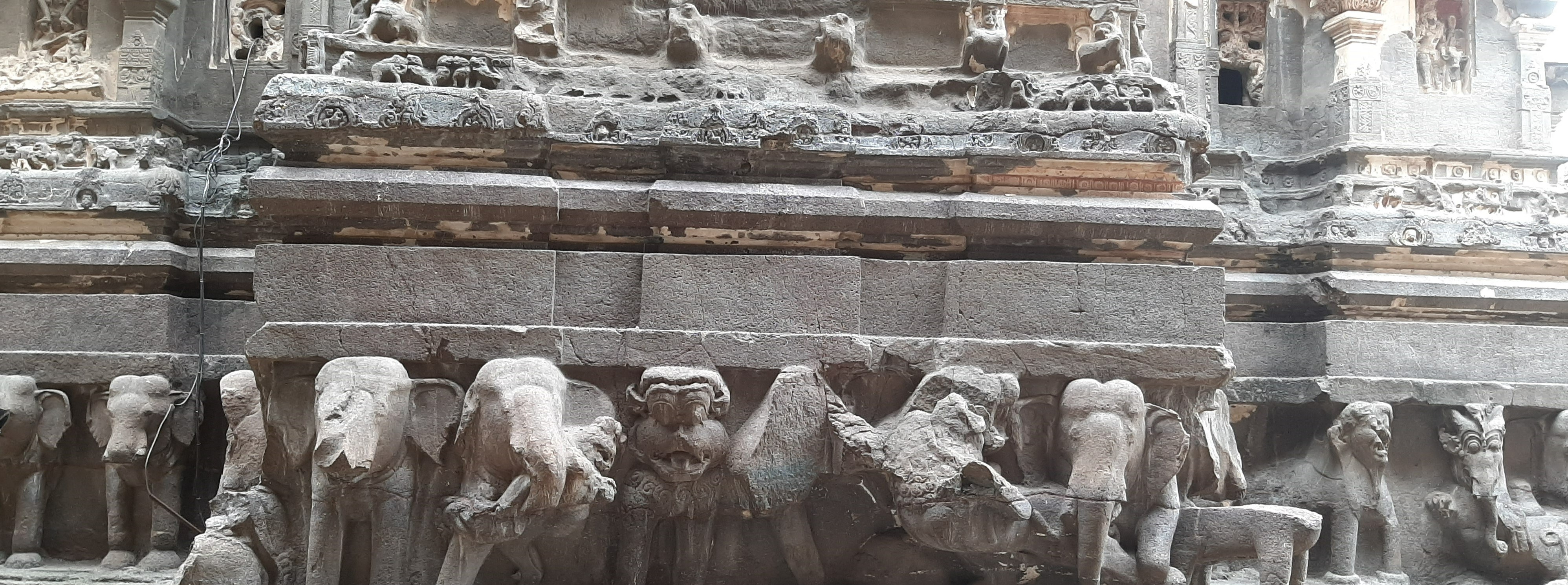 Life-sized elephants carved in relief around the base of the temple plinth, appearing to bear its weight.