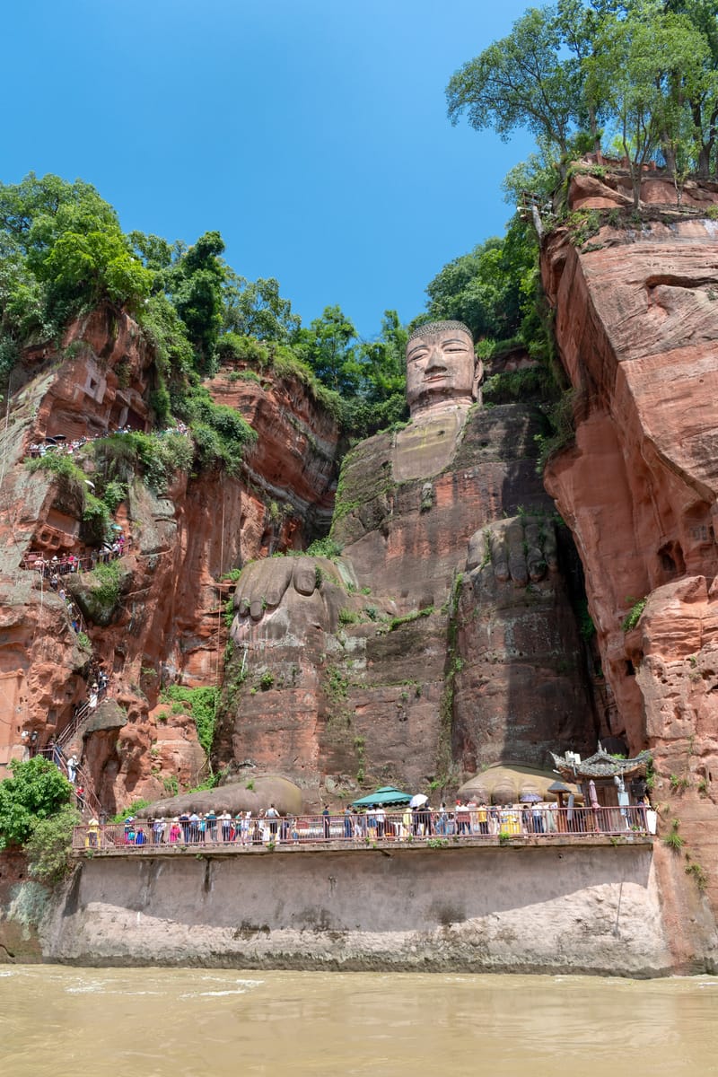 The Buddha framed by the wooded cliff of Mount Lingyun above the confluence of the Min, Dadu, and Qingyi rivers.