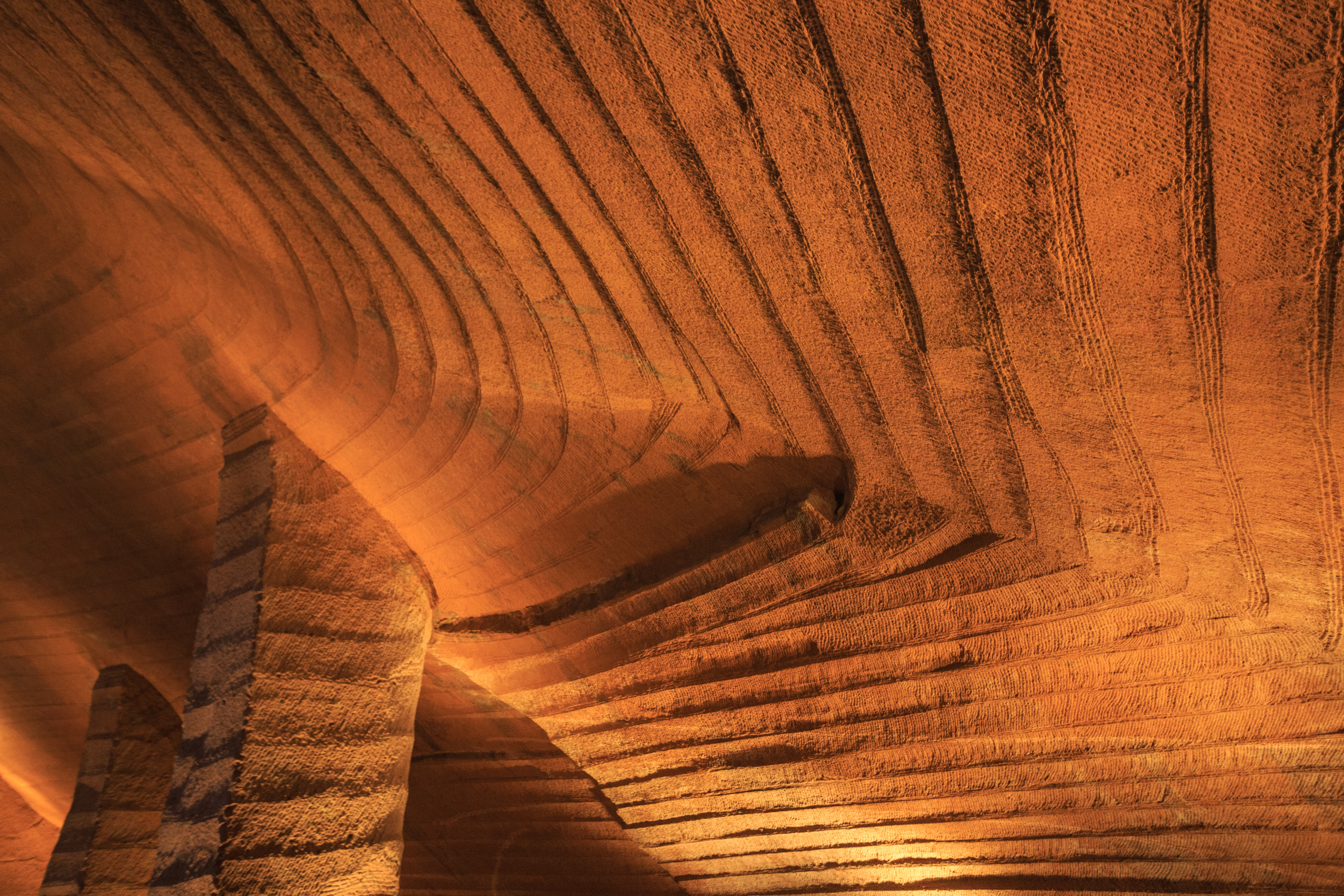 Close-up of the ceiling's fan-shaped, evenly spaced parallel chisel marks, tooled at a consistent angle across every chamber.