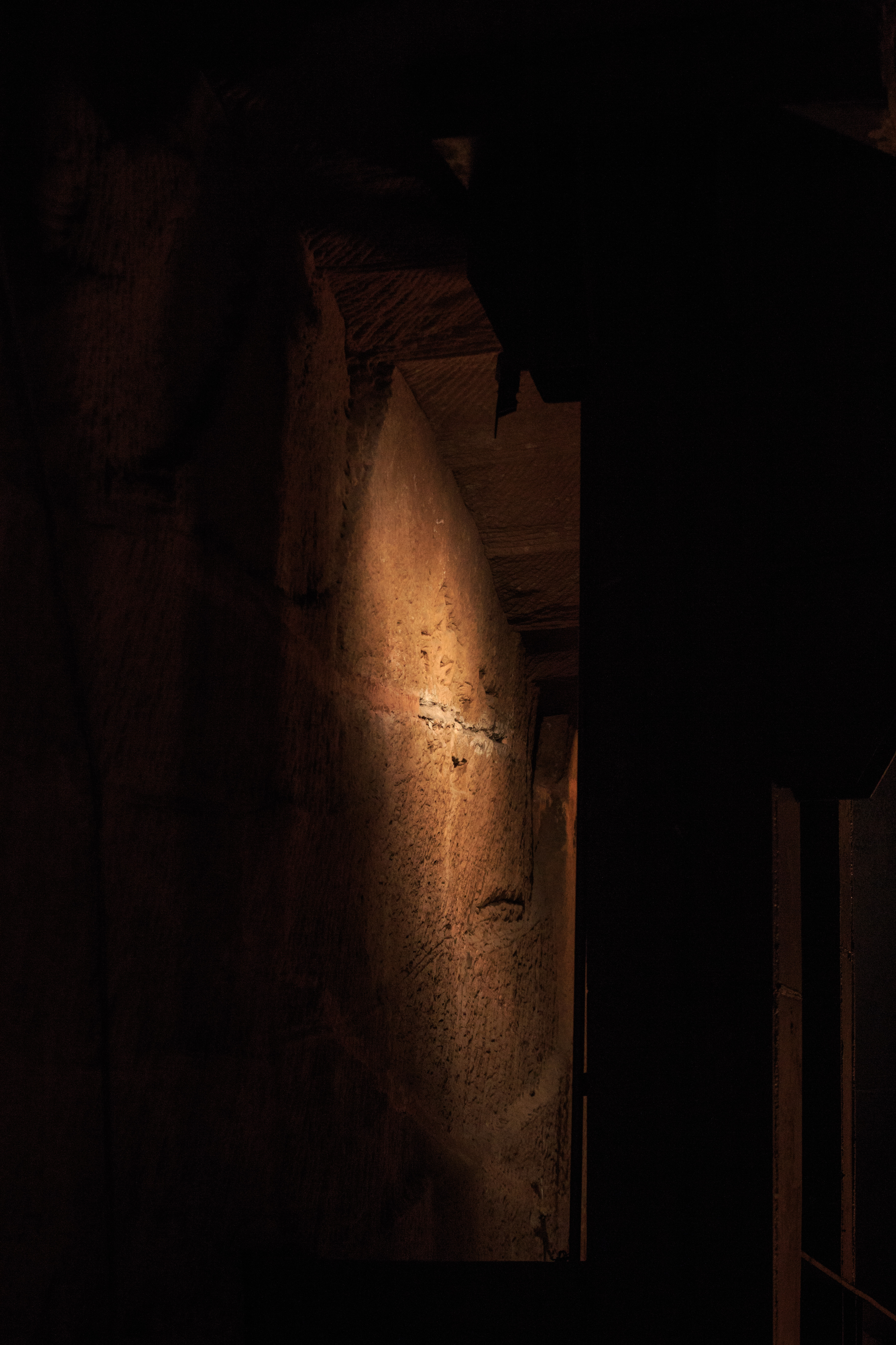 One of the load-bearing stone pillars left standing during excavation, its surface carved with the same uniform tool marks as the walls and ceiling.
