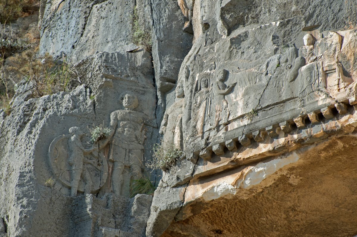 Relief figures beside a tomb at Myra, above a row of carved dentils — the decorative course that began life as the exposed ends of real roof beams.