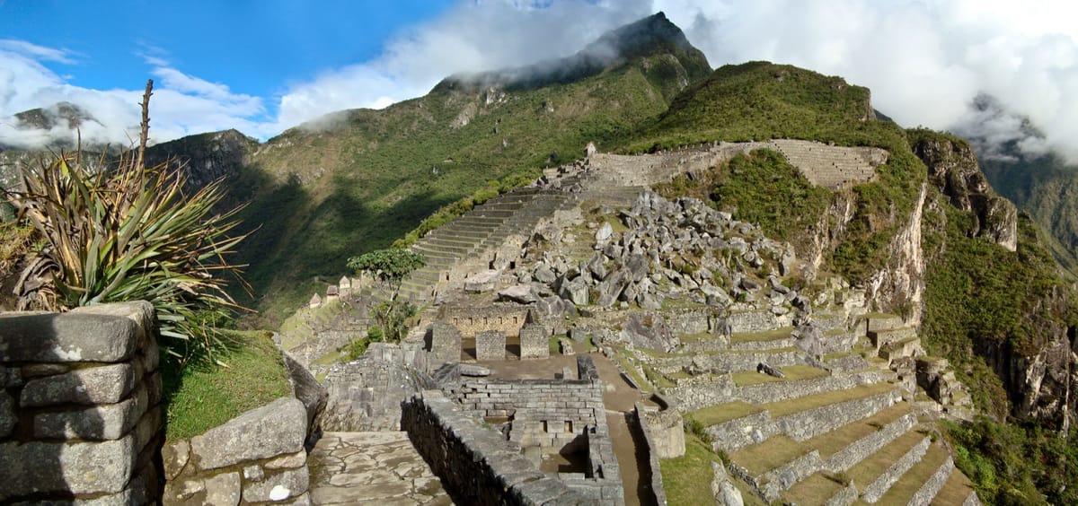 The temple zone and agricultural terraces stepping down the ridge, engineered in graded layers of stone, gravel, and topsoil to drain the site's heavy rainfall.