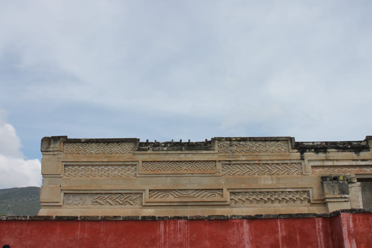 Bands of grecas on the palace facade. Each band runs a different geometric pattern — the vocabulary of motifs is small, but no panel at Mitla repeats another exactly.