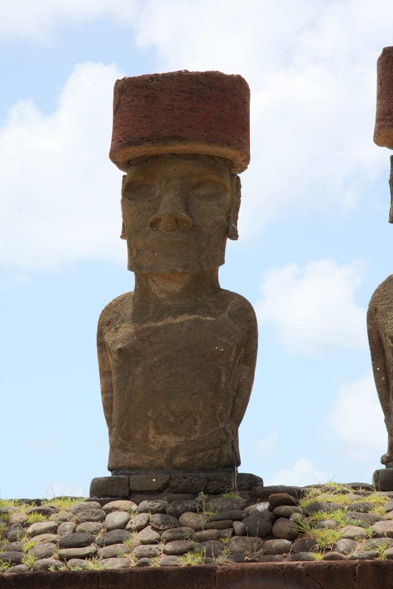 A moai at Ahu Nau Nau, Anakena, still wearing its pukao — a separately carved cylinder of red volcanic scoria quarried at Puna Pau.