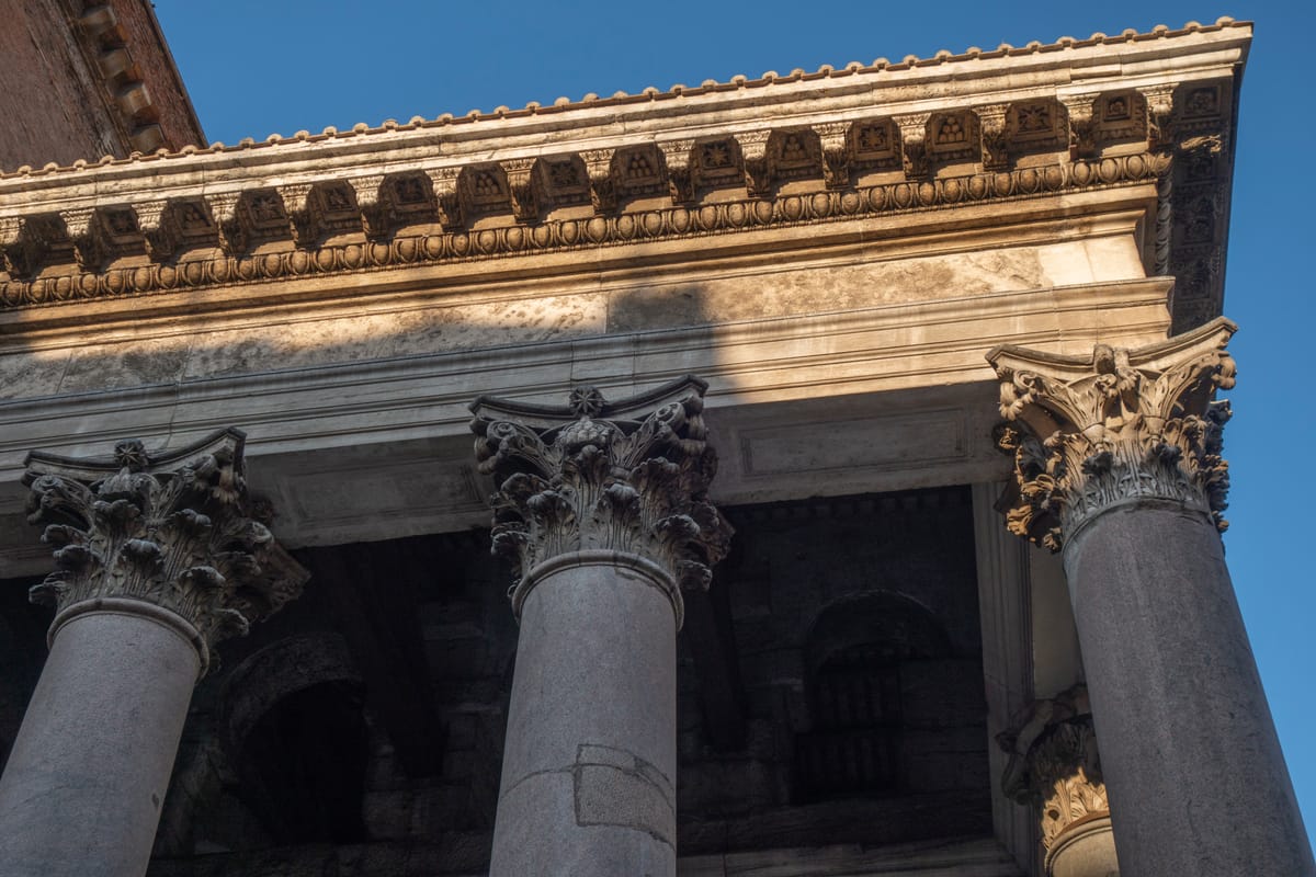 Corinthian capitals and entablature of the portico, carried on monolithic granite shafts quarried in Egypt and shipped the length of the Mediterranean.