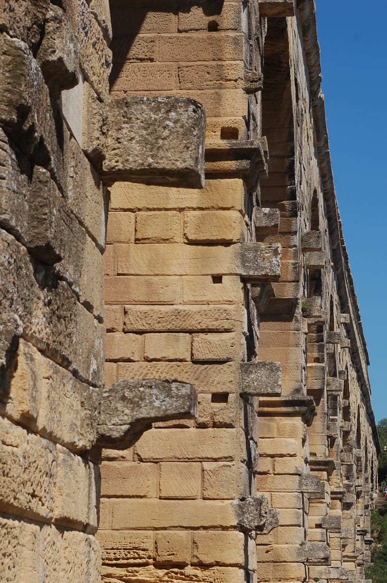 Blocks left deliberately projecting from the piers — the seatings for the timber scaffolding and centring used during construction, never trimmed away after the bridge was finished.