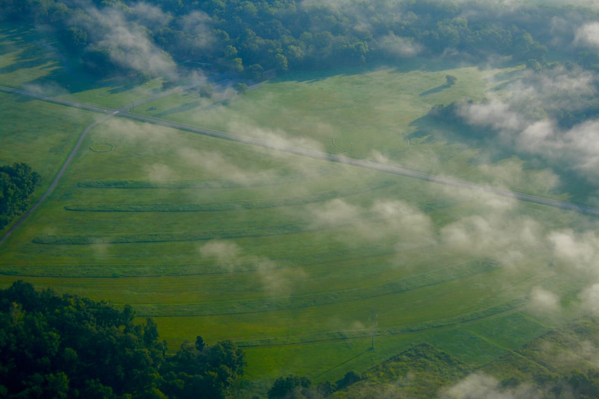 Aerial view of the concentric earthen ridges at Poverty Point, with two modern marker rings showing the positions of ancient timber post circles found in the plaza.