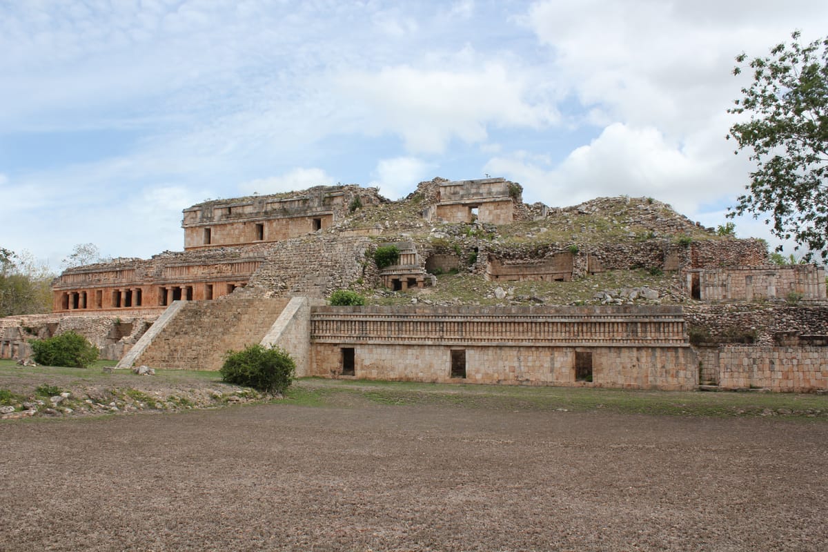 The palace seen across the plaza: rubble-and-mortar terraces support each successive range of rooms, and the collapsed upper levels expose the concrete core beneath the veneer.