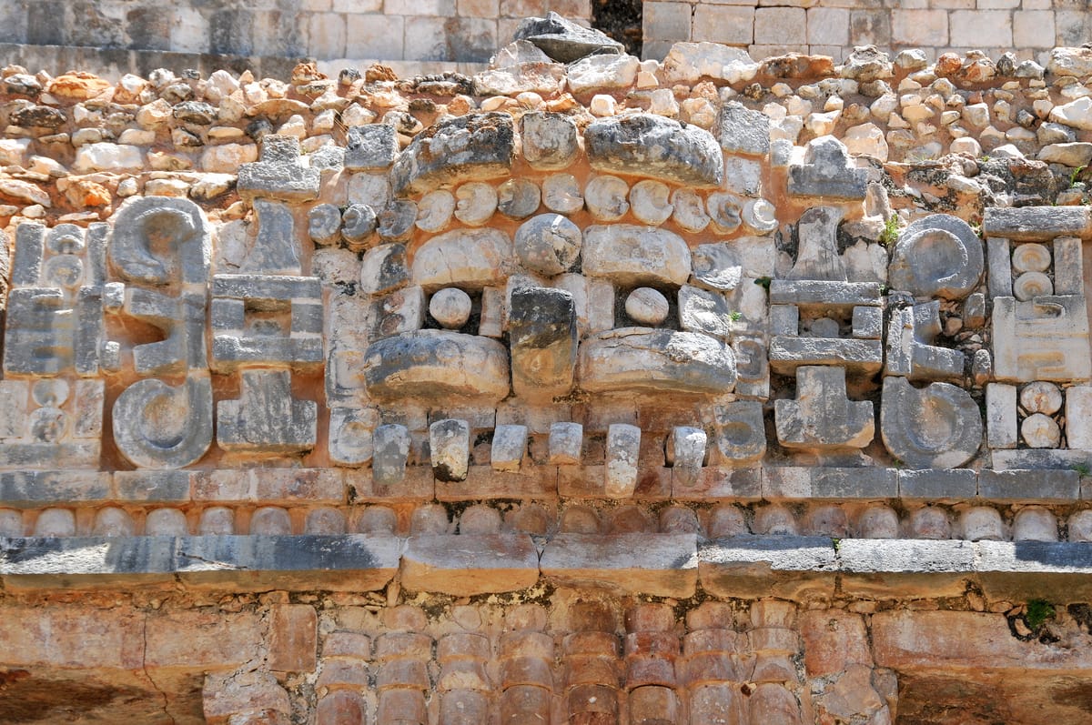 A mosaic mask of Chaac, the rain god, assembled from dozens of separately carved veneer stones on the palace's central level.