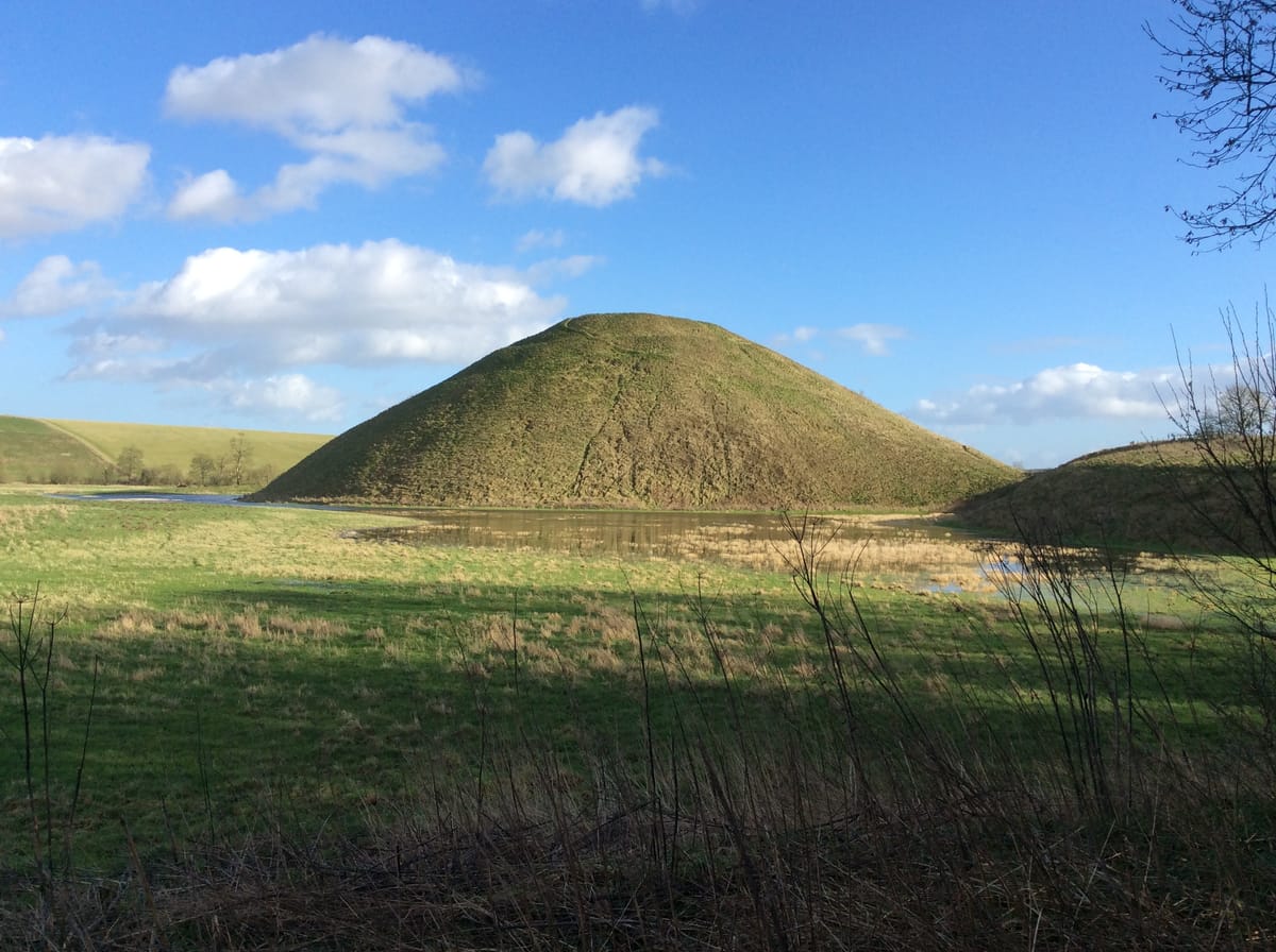 Silbury Hill seen from the surrounding Wiltshire farmland, showing its stepped, terraced profile.