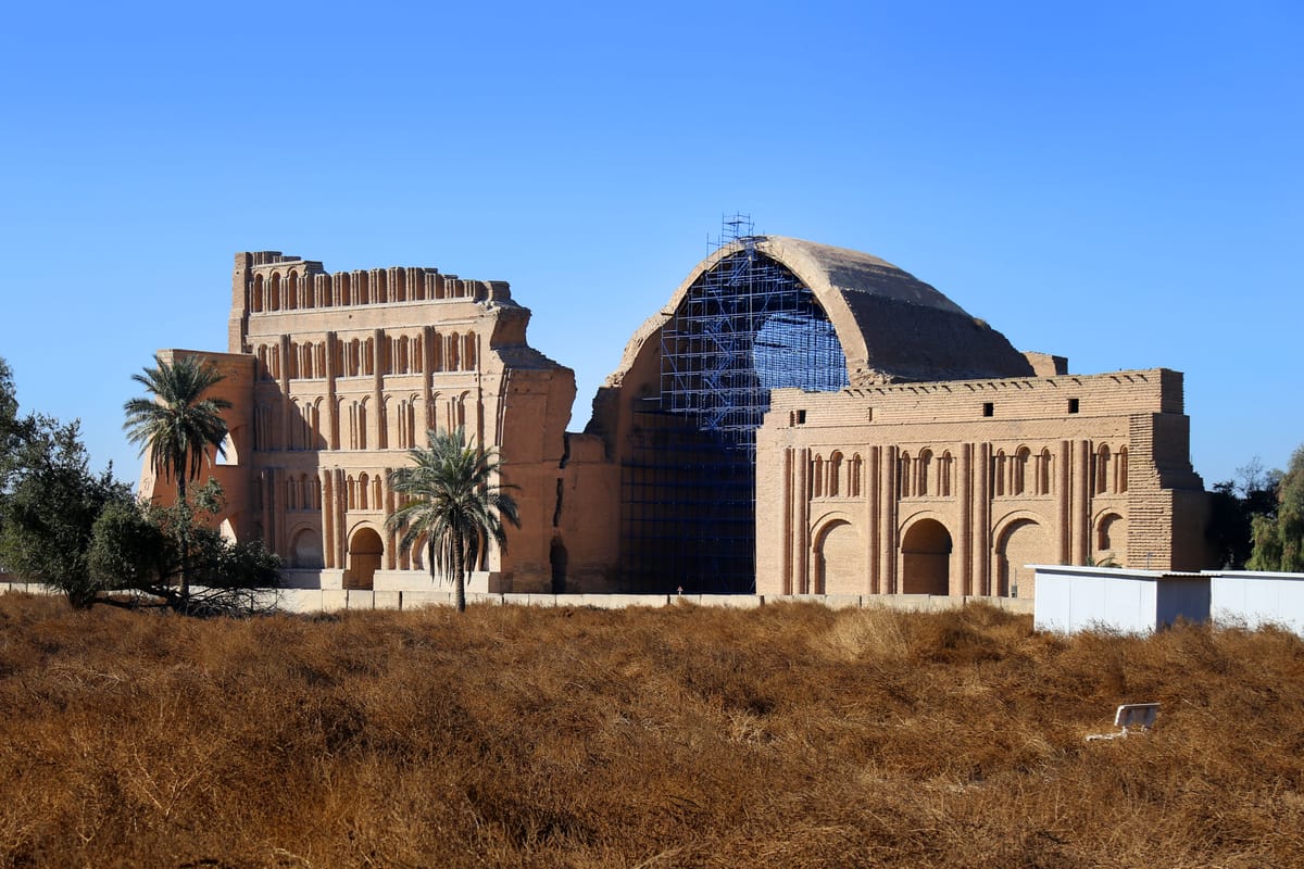 Taq Kasra in 2022: the surviving southern wing of the blind-arcaded facade at left, the great vault at right under restoration scaffolding and netting.
