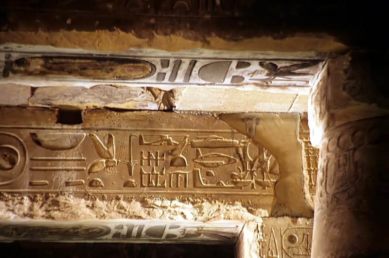 The 'Abydos helicopter' architrave — an eroded palimpsest where Seti I's original titulary and Ramesses II's re-carved titulary overlap, once the plaster infill fell away. The shapes some read as aircraft are simply superimposed hieroglyphs.