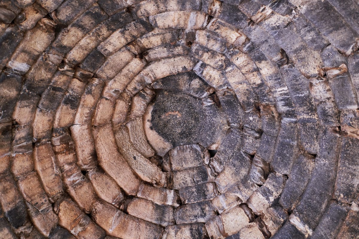 Straight up at the apex: thirty-three concentric rings of stone, each laid a little further in than the one beneath, closing to a single capstone with no keystone anywhere in the structure.