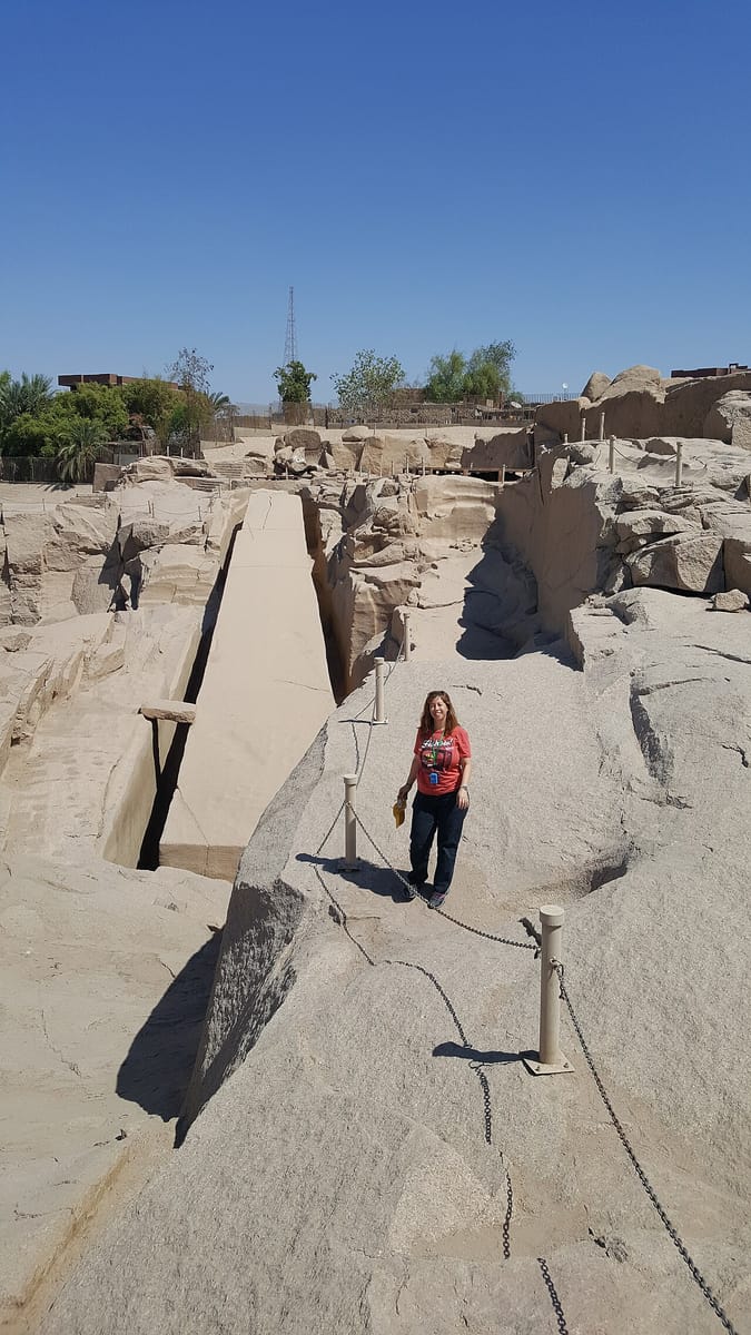 A visitor standing beside the obelisk's trench gives a sense of scale — the cut runs several meters deep into the granite bedrock.
