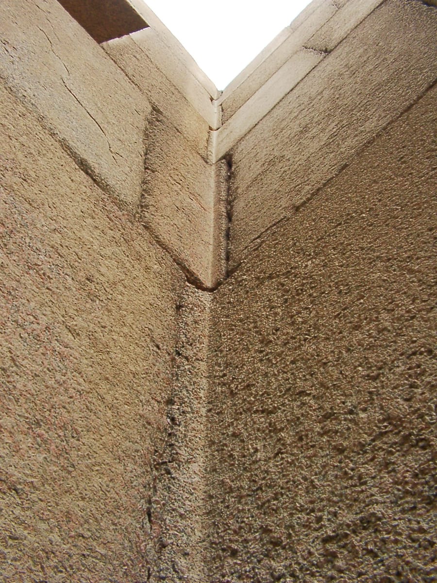 A corner of the granite casing, where L-shaped ('bent') blocks are cut to wrap around the angle and interlock with their neighbours — the kind of tight, multi-angled jointing that draws so much attention to the temple.