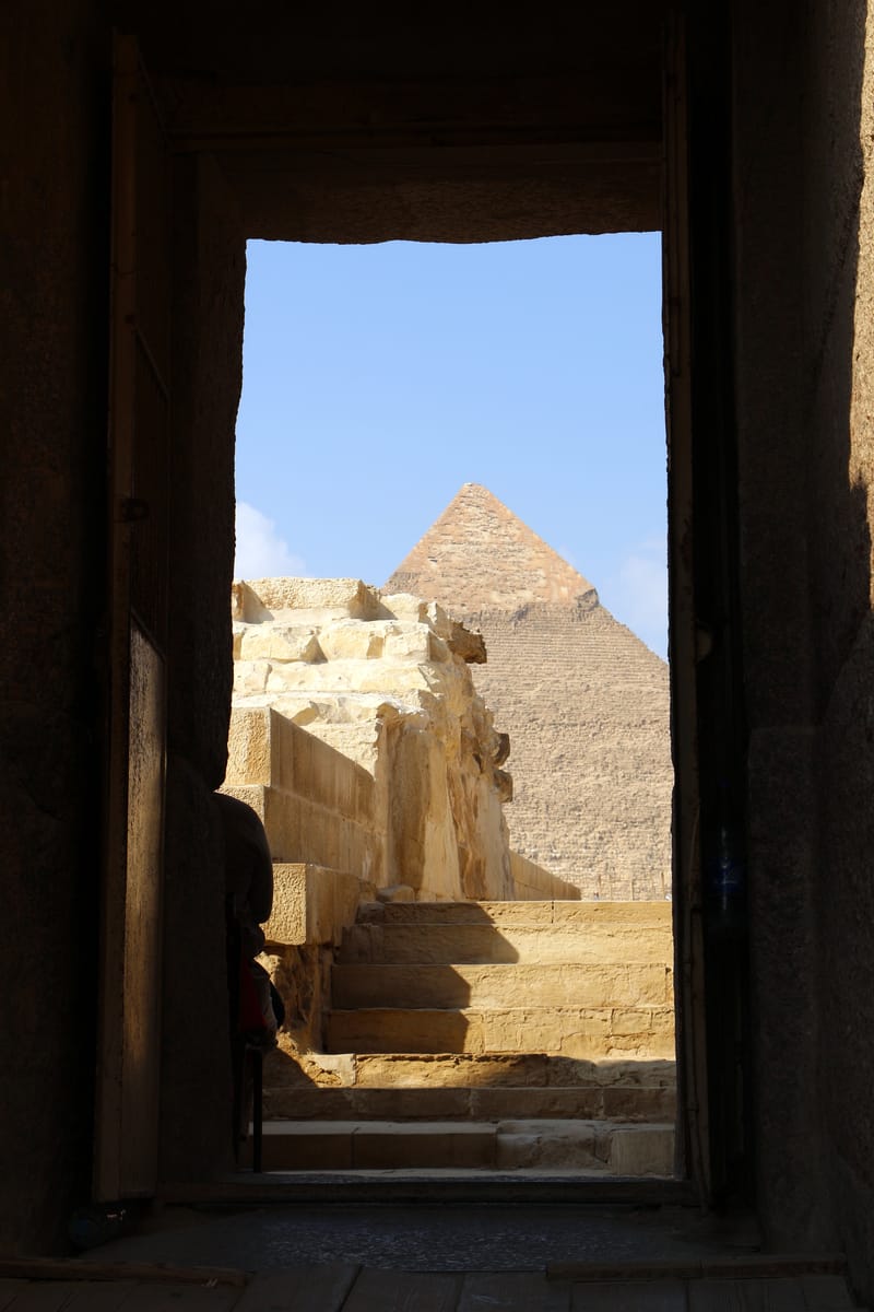 Looking out from a doorway of the valley temple toward the Pyramid of Khafre — the two ends of a single funerary complex linked by a causeway nearly half a kilometre long.