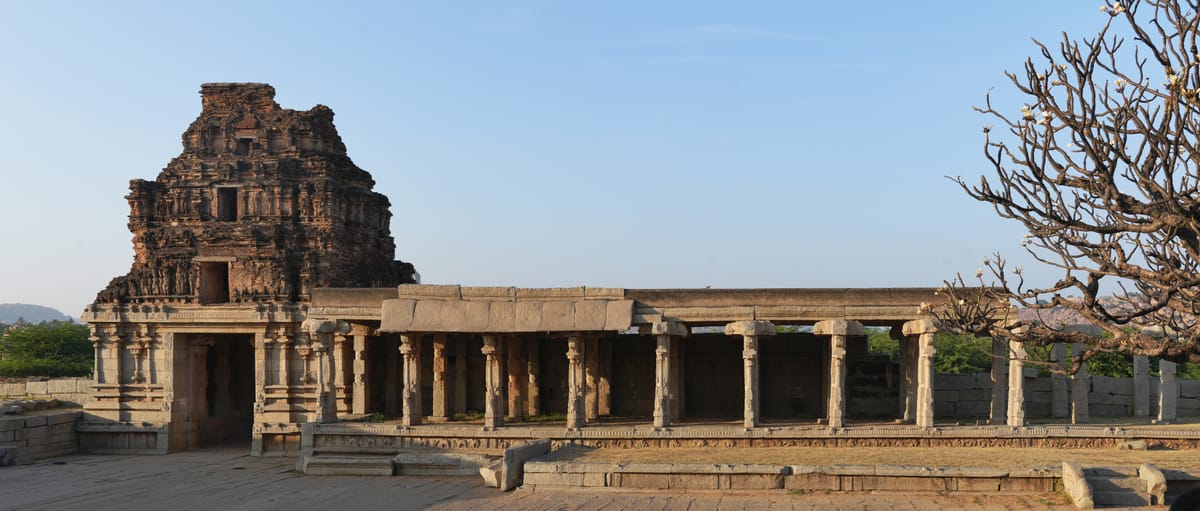 A gopuram gateway and pillared hall within the walled Vittala enclosure, left unfinished when the Vijayanagara capital fell in 1565.