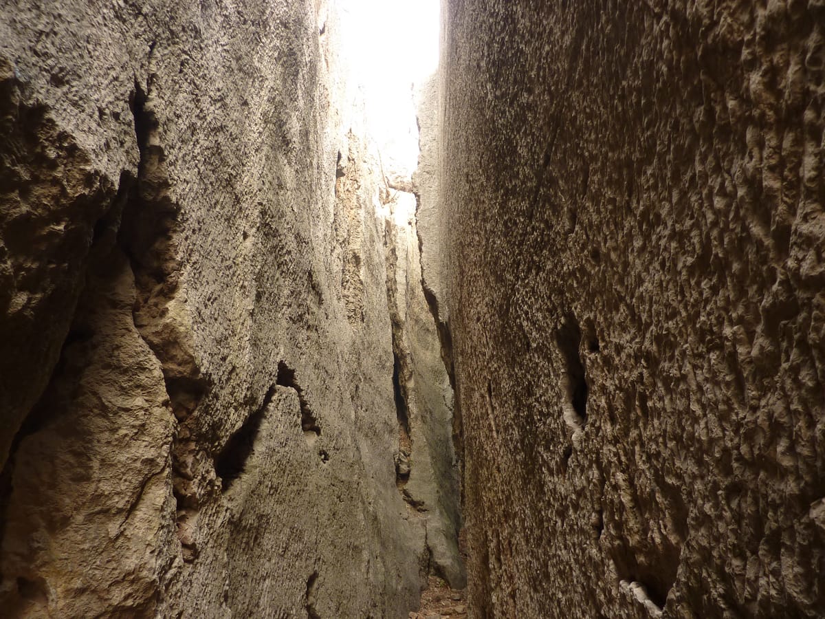A narrow quarried channel separating the stele body from the surrounding mountain rock, showing how workers cut galleries around each block to free it.