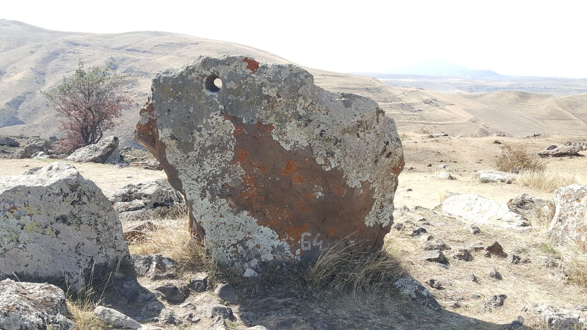 Close view of one of the roughly 80 stones with a smoothly bored circular hole through its upper section.